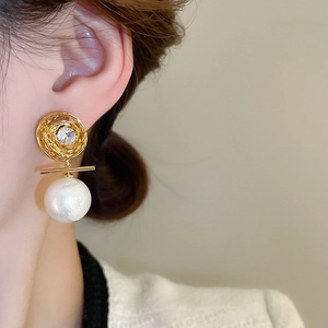 Gros plan d'une boucle d'oreille en perle dorée avec zircone portée par un mannequin