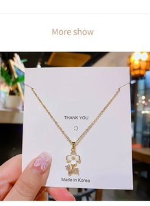 Detail of gold flower necklace with white petals and shimmering zircon leaf accents