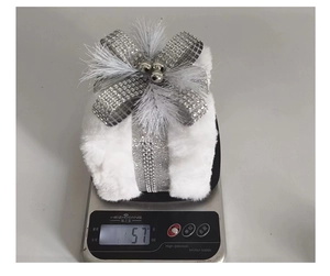 Detailed view of plush white Christmas gift box ornament on scale weighing 57 grams