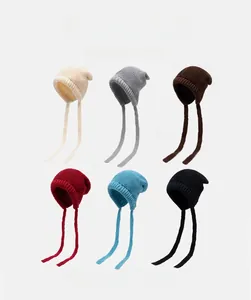 Detailed view of six knit hats with earflaps and long ties in various soft colors