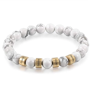 Detail showing custom engraved names on golden metal spacers with white stone beads