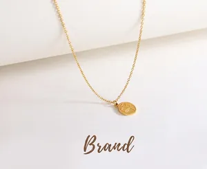 Detailed view of an oval leaf pendant necklace on a gold chain over an elegant table setting