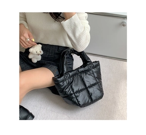 Detail of black quilted puffer handbag with a cute white plush bear pendant decor