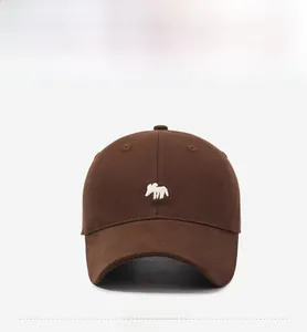Close-up of small white animal embroidery on a dark brown cotton baseball cap front