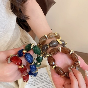 Detail of colorful oval acrylic beaded bracelets with gold irregular spacer accents