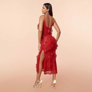 Detail of red sequin evening dress featuring ruffles, backless straps, and a high slit