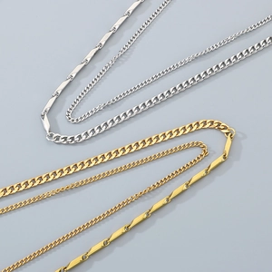 Detail showing layered silver and gold Cuban curb chains with sleek Figaro bar links