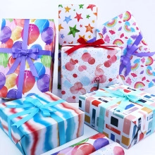 Stacked gift boxes featuring colorful balloons, stars, and rainbow patterns with ribbons