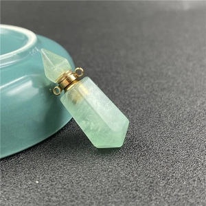 Nahaufnahme einer grünen Kristallparfümflasche als Anhänger mit goldenem Sechskantprisma