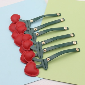 Detailed view of red cherry-shaped leather cable organizers with golden metal snaps