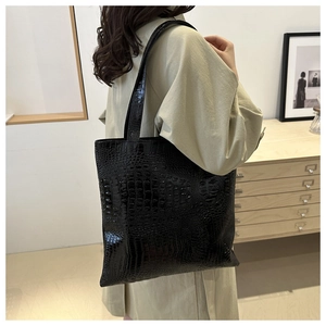 Detailed view of black crocodile pattern tote bag shown from a side perspective on a model