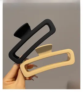 Detail of matte rectangular hair claws in black and beige with a frosted finish