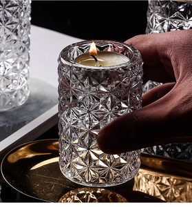 Macro shot of faceted crystal glass candle holder with warm tea light and golden metal tray