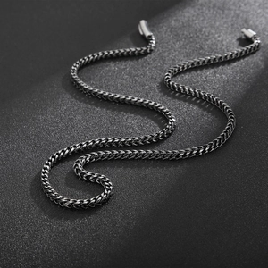 Detail of gun-black dragon bone link chain with industrial wheat-braid texture