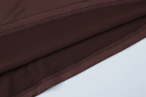 Dettaglio del tessuto in maglia marrone scuro con cuciture a doppio ago e consistenza