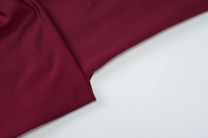 Macro shot of dark red fine knit fabric texture and elegant draping on summer maxi dress