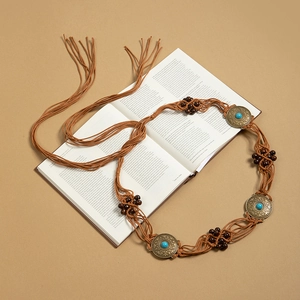 Détail de chaîne de taille tressée bohème avec pierres turquoises sur un livre ancien