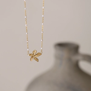 Detail of flower pendant necklace in 18K gold finish with elegant white beads