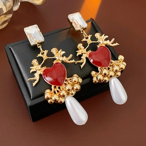 Detail of vintage angel earrings with red heart enamel and white drop pearl pendant