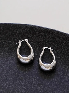 Detailed view of chunky silver teardrop hoop earrings with a polished mirror finish