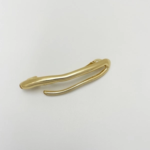 Detail of a sleek gold-tone irregular spring hair clip with a polished fluid metal finish