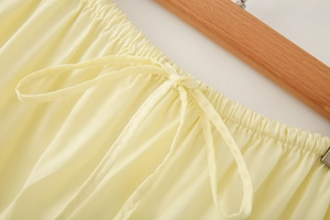 Detail of light yellow tiered skirt featuring an elastic drawstring waistband and matte fabric