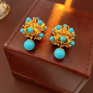 Gros plan détaillé de boucles d'oreilles vintage dorées avec perles turquoise sur cuir