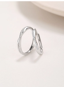 Macro detail of silver Mobius couple rings featuring twisted texture and pave diamond setting