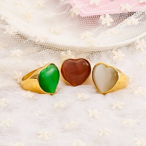 Three gold heart-shaped stainless steel rings with cat eye stone inlays on white lace