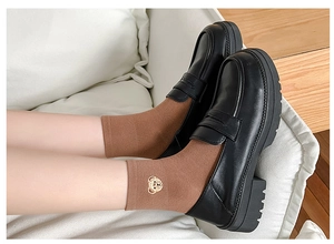 Close-up of cute bear embroidery on brown cotton ankle socks with black platform loafers