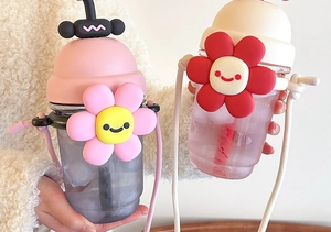 Detail of cute sunflower plastic straw cups in pink and beige with crossbody straps