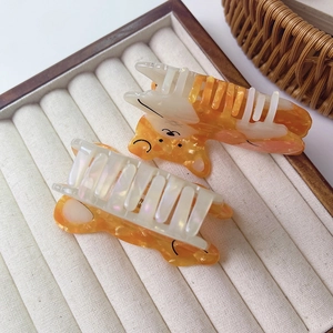 Detail of bear-shaped acetate hair clips with orange marble and pearly ivory finish