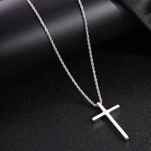 Macro shot of polished silver cross pendant with twisted rope chain on silk background