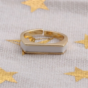 Detail of adjustable gold-plated ring featuring a white enamel geometric rectangle top