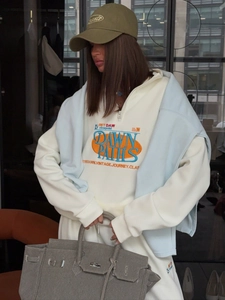 Détail d'un sweat-shirt beige demi-zip avec broderie de lettres de style vintage