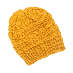 Close-up of ginger yellow knit beanie showing thick cable patterns and ribbed cuff detail