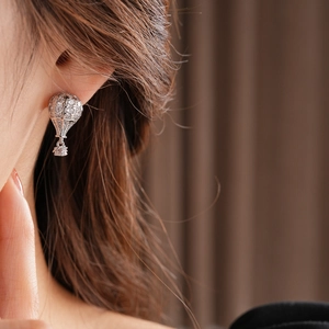 Gros plan de boucles d'oreilles ballon en argent avec zircons sur l'oreille