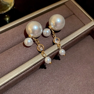 Close-up of elegant gold tassel earrings with white pearls and sparkling zircons