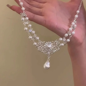 Gros plan du collier fleur en perles et strass avec pendentif goutte en finition argent