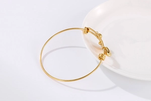 Detail of adjustable gold-plated bangle showing the slider closure and heart charm