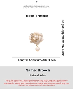Vue détaillée d'une broche camélia blanc avec bords dorés, croissant et perle pendante