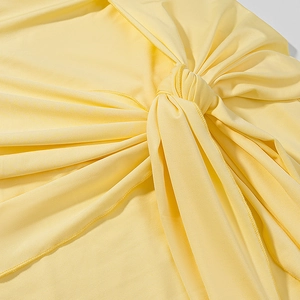Yellow off-shoulder knit dress with elegant waist knot detail and draped texture