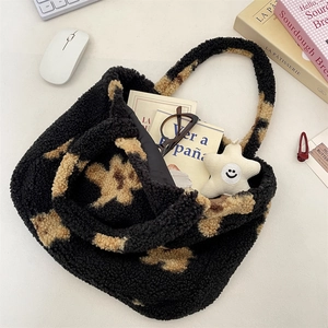 Close-up of fuzzy teddy tote bag with star patterns, books, and smiley face charm