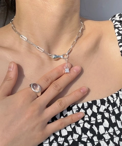 Detail shot of a minimalist S925 silver necklace with square gemstone and a wide ring