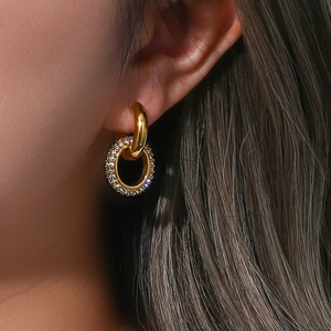 Detail of gold-plated double hoop earrings with cubic zirconia on a female model