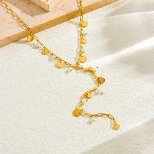 Detail of a gold Y-shaped necklace featuring small round pendants and light blue beads