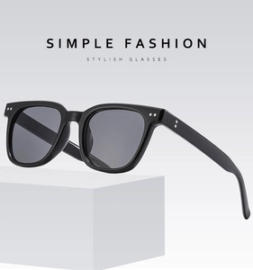 Close-up of black square polarized sunglasses with decorative metal rivets on a white stand
