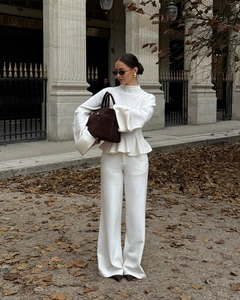 Détail d'un ensemble en maille blanc crème avec haut à ourlet volanté et pantalon large