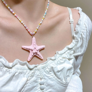 Detail of pink starfish pendant with colorful beads on a summer beach necklace