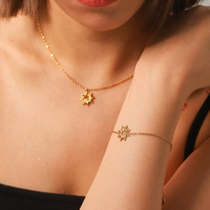 Golden sunburst pendant necklace and matching bracelet set with crystal inlay on a model
